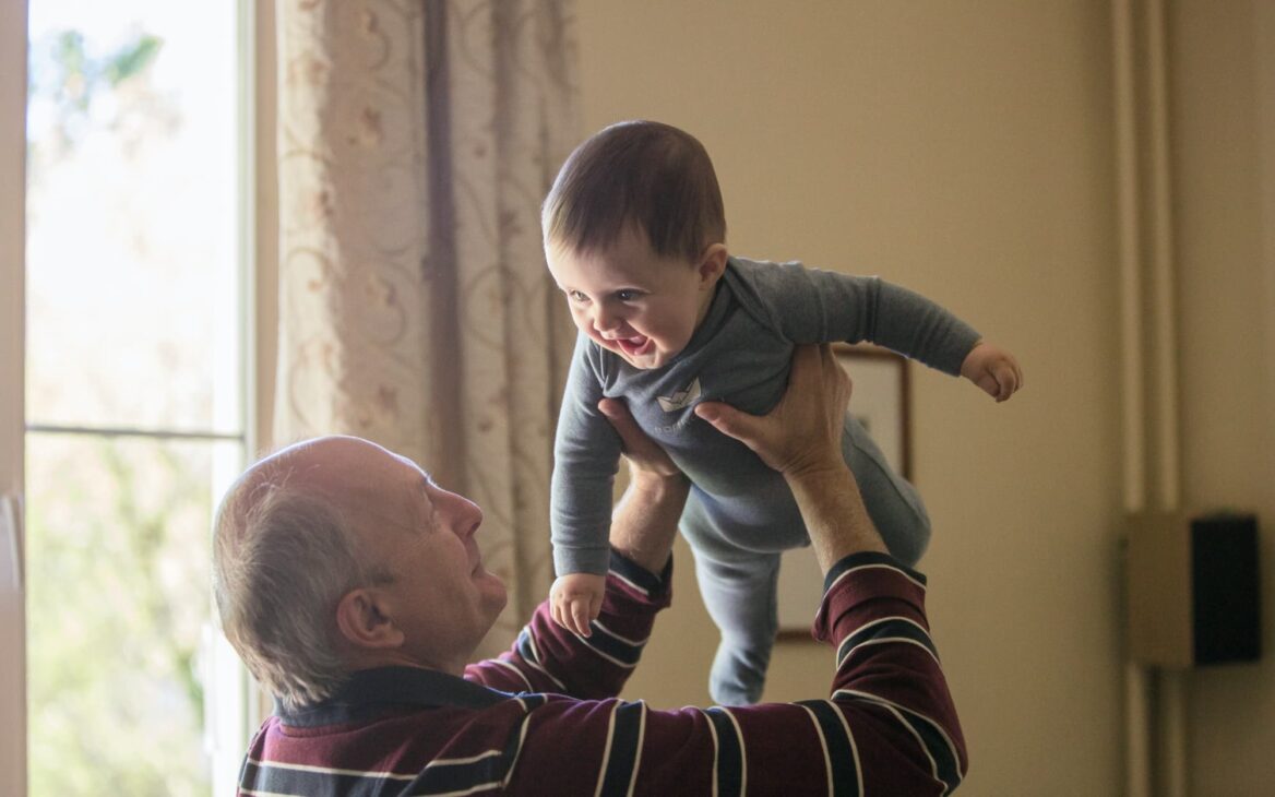 Grandfather holds grandson in his arms.