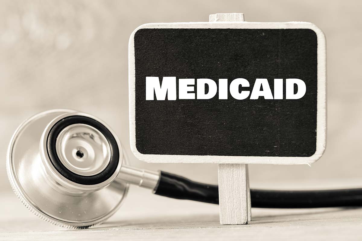 A small chalkboard with the word "Medicaid" written on it next to a stethoscope.