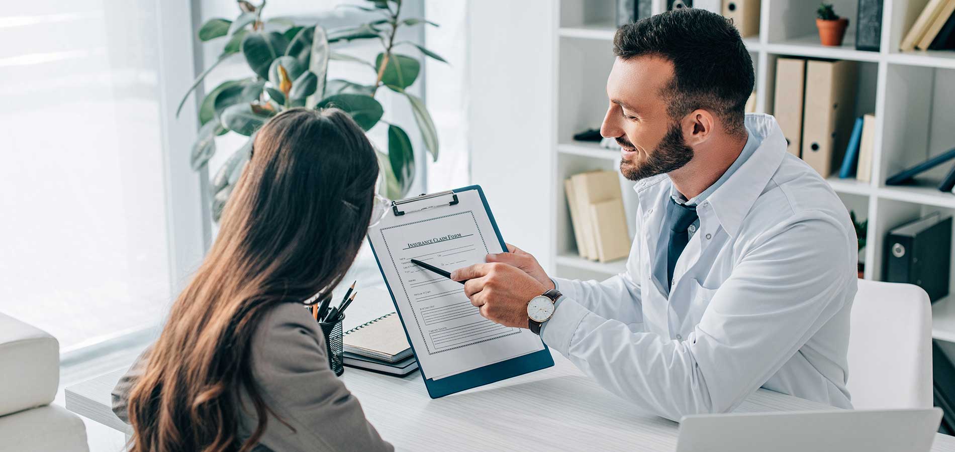 A man in a blue shirt reviews a document with a woman in an office setting.