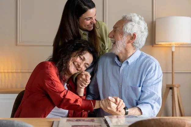 An older man and woman sit at a table holding hands and smiling, while a younger woman stands behind them, also smiling.